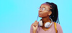 Black woman, thinking and gen z person with student vision and ideas in a studio copy space. Blue background, university students idea and headphones of a young female with glasses contemplating with pencil