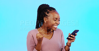 Black woman, smartphone and fist for celebration, lucky winner and achievement against a blue studio background. African American female, happy lady and cellphone with email, social media and victory