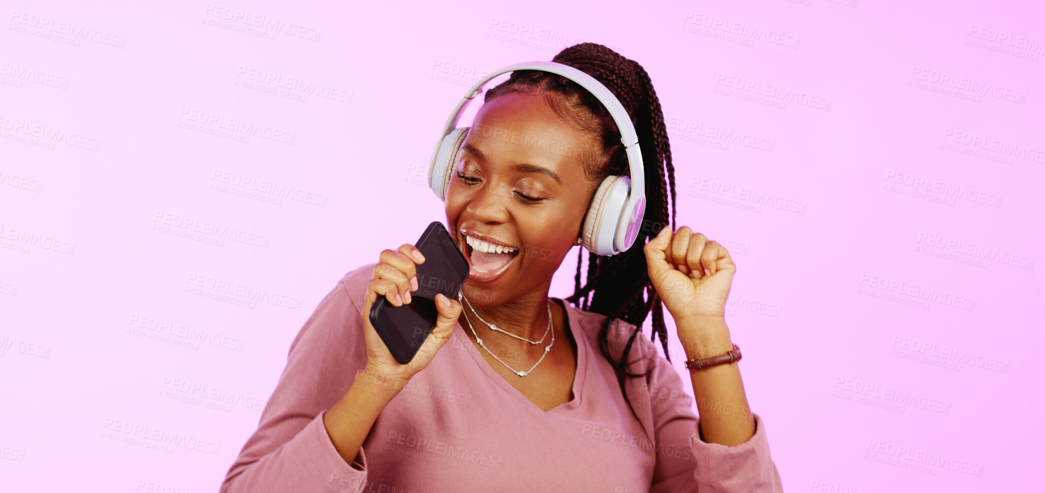 Buy stock photo Singing, music and black woman dance with headphones, phone or microphone on pink background in studio. Happy, audio and listening to radio, sound or hip hop rapper sing with energy and dancing