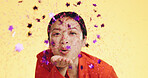 Studio, asian woman blowing confetti and celebration for birthday, anniversary or celebrating Chinese new year. Happy party, smile and model from china on yellow background to celebrate with glitter