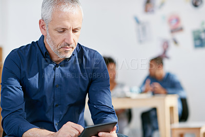 Buy stock photo A businessman using a digital tablet in a creative office or startup. CEO working online for web development and app design