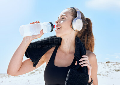 Buy stock photo Beach, workout and drinking water with headphones music for exercise, fitness and training break. Wellness, relax and sport woman streaming audio and resting body after cardio with water hydration.