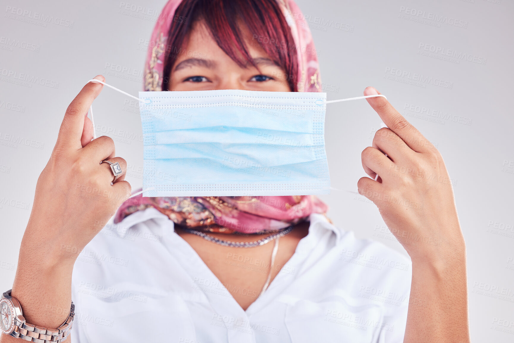 Buy stock photo Covid, mask and safety with a muslim woman in studio on a gray background for a new normal lifestyle. Compliance, health and safe with an islamic female show how to wear a face mask during pandemic