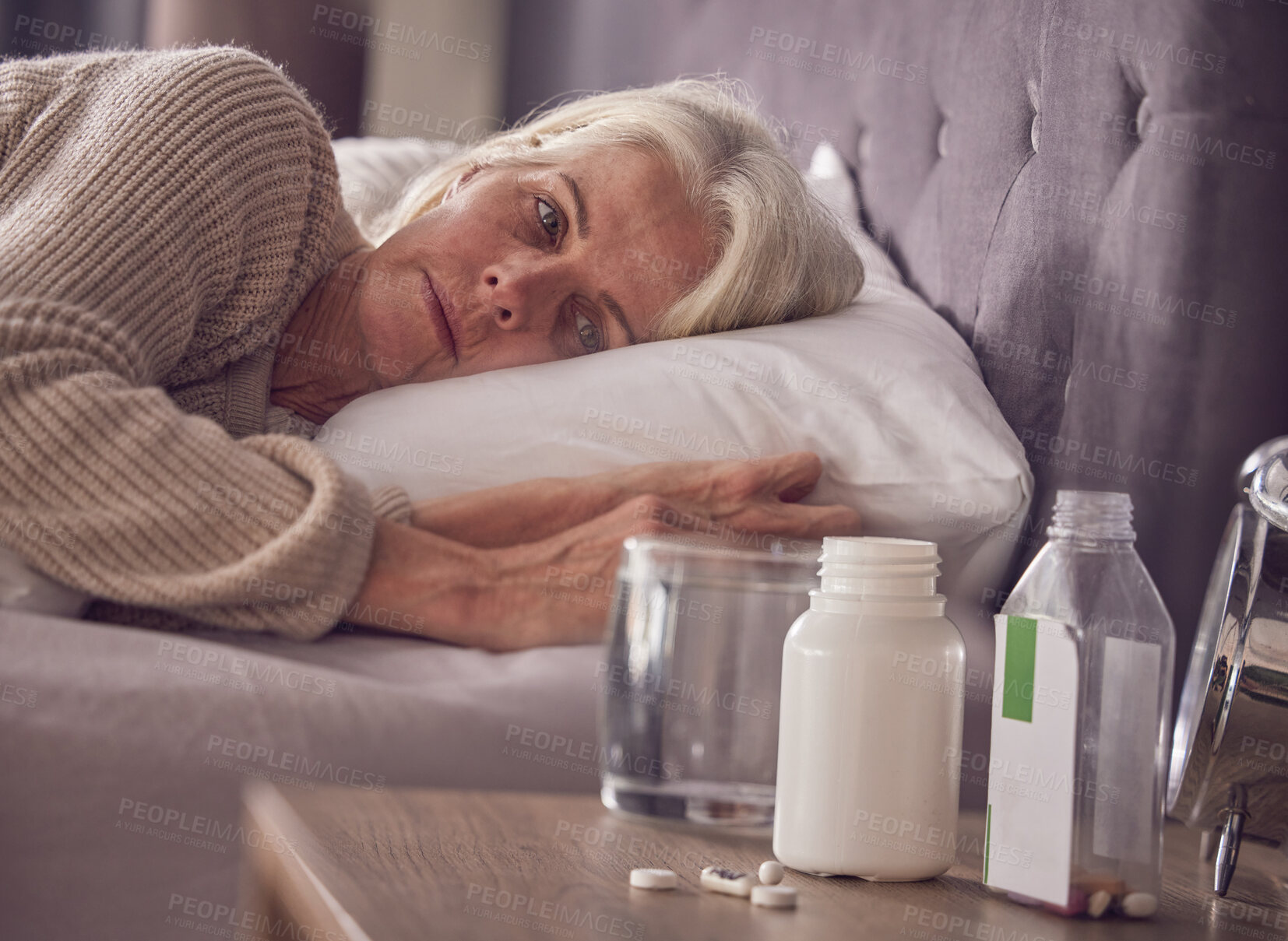 Buy stock photo Elderly woman, bed and medical addiction with pills, medicine or medication while lying awake at home. Senior female suffering from sick, illness or mental health, trauma or disorder in the bedroom