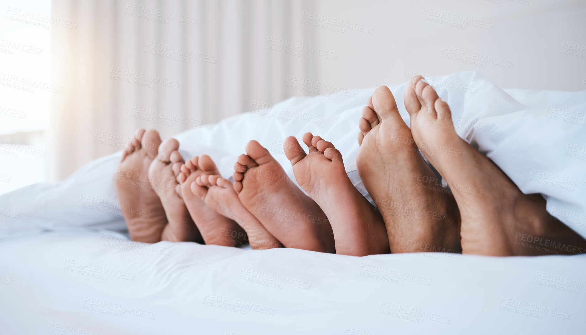 Buy stock photo Family, feet in bed and in bedroom of their home with a lens flare sleeping together. Resting or barefoot, relaxing and parents with toes of their children comfortable in the morning of their house.