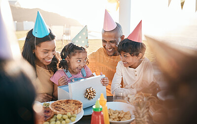 Buy stock photo Birthday, party and family outdoors for celebration, bonding and present, happy and excited. Parents, children and gift for girl child at special event, smile and celebrating with food at restaurant 