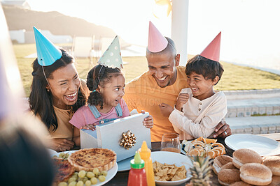 Buy stock photo Happy birthday, love and family outdoors for celebration, party and present, laugh and excited. Parents, children and gift for girl child at special event, smile and celebrating with food outside