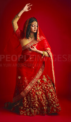Buy stock photo Fashion, dancing and Indian woman in a traditional dress, celebration and confident on a red studio background. Female person, girl and model with a cultural outfit, dancer and ritual with confidence