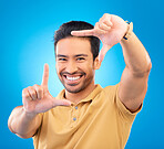 Portrait, finger frame and man in studio, blue background and review profile picture. Face, happy male model and hands for planning perspective of photography, selfie and inspiration of photographer 