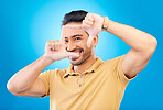 Asian Man, smile and frame hands in portrait for perspective in blue background with vision or confidence. Happy male, face and finger framing for selfie and profile or holding hand out in studio.