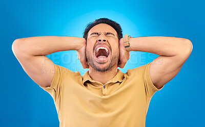 Buy stock photo Man cover his ears while shouting in a studio for angry, upset or mad argument expression. Crazy, scream and young male person with an open mouth for loud voice gesture isolated by a blue background.