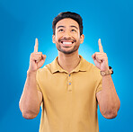 Smile, casual and man pointing up, promotion and opportunity against a blue studio background. Male person, guy and model with happiness, mockup space and direction with choice, happy and decision
