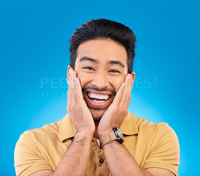 Happy, excited man and smile portrait in studio with Asian model with teeth and joy. Blue background, male person and casual fashion with handsome and friendly guy with modern style and wow face