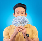 Cash, fan and man with wow face isolated on blue, studio background for winning, money surprise or financial success. Lottery, finance secret and asian person winning, bonus and cashback in portrait