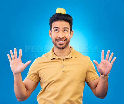 Buy stock photo Funny, Asian man and balance apple on head for comedy, trick or a show. Happy, young and a comic person with balancing fruit on hair for diet or nutrition isolated on a blue background in a studio