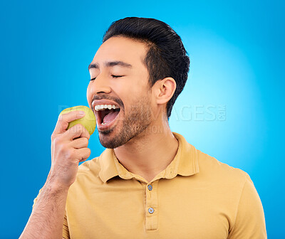 Buy stock photo Hand, man eating an apple and against a blue background for healthy diet. Nutrition or mockup space, isolated or green food and male person eat fruit for health wellness against a studio backdrop