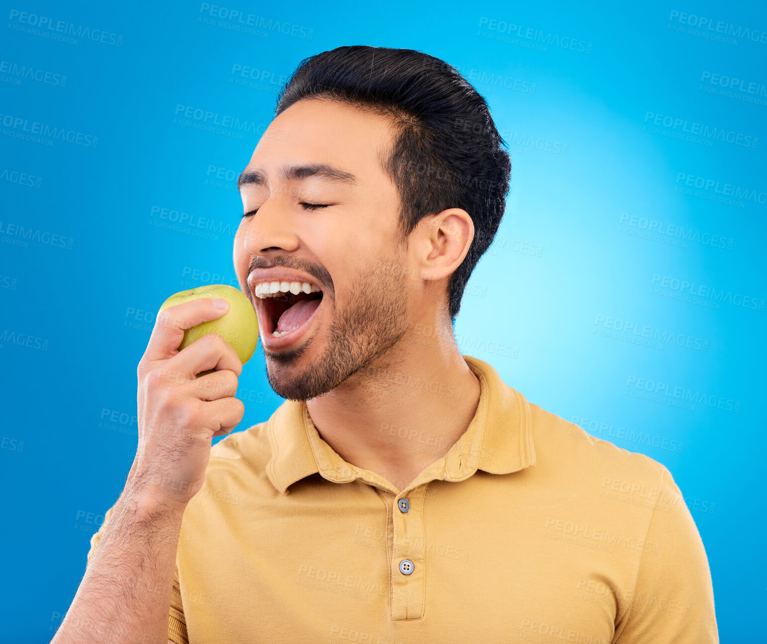 Buy stock photo Hand, man eating an apple and against a blue background for healthy diet. Nutrition or mockup space, isolated or green food and male person eat fruit for health wellness against a studio backdrop