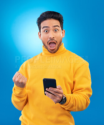 Buy stock photo Winner, surprise and portrait of Asian man with phone in studio for online bonus, competition and prize. Success, smartphone and face of male person on blue background with promotion, winning and wow