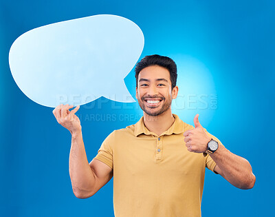 Buy stock photo Young man, speech bubble and studio portrait for thumbs up, opinion and social network by blue background. Indian guy, student or model for yes icon, mock up space and cardboard sign for promotion