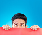 Eyes, poster and mockup with a man hiding in studio isolated on a blue background for advertising information. Space, sign and a male brand ambassador showing an empty placard for a marketing logo