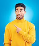 Man, point and thinking in studio with shock face for ideas, fashion and promotion with choice by blue background. Young Indian guy, student and finger for decision, icon and opinion with surprise