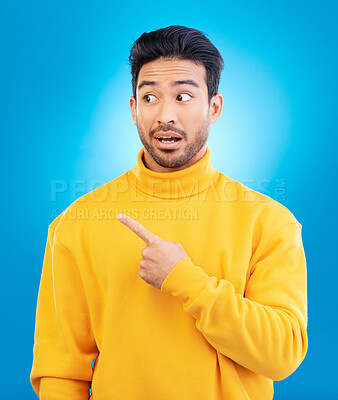 Buy stock photo Man, point and thinking in studio with shock face for ideas, fashion and promotion with choice by blue background. Young Indian guy, student and finger for decision, icon and opinion with surprise