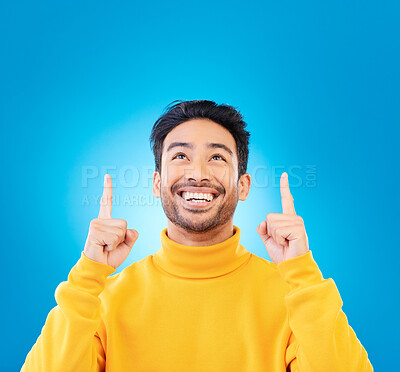 Buy stock photo Happy, casual and man pointing up, promotion and winning against a blue studio background. Male person, guy or model with happiness, mockup space and decision with choice, excited and creative design