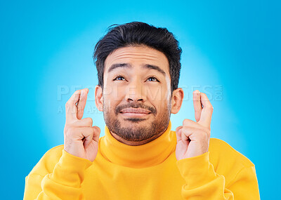 Buy stock photo Hope, man with his fingers crossed for luck and against a blue background for thinking. Praying or miracle, trust and male person with hand emoji for aspiration or idea against a studio backdrop.