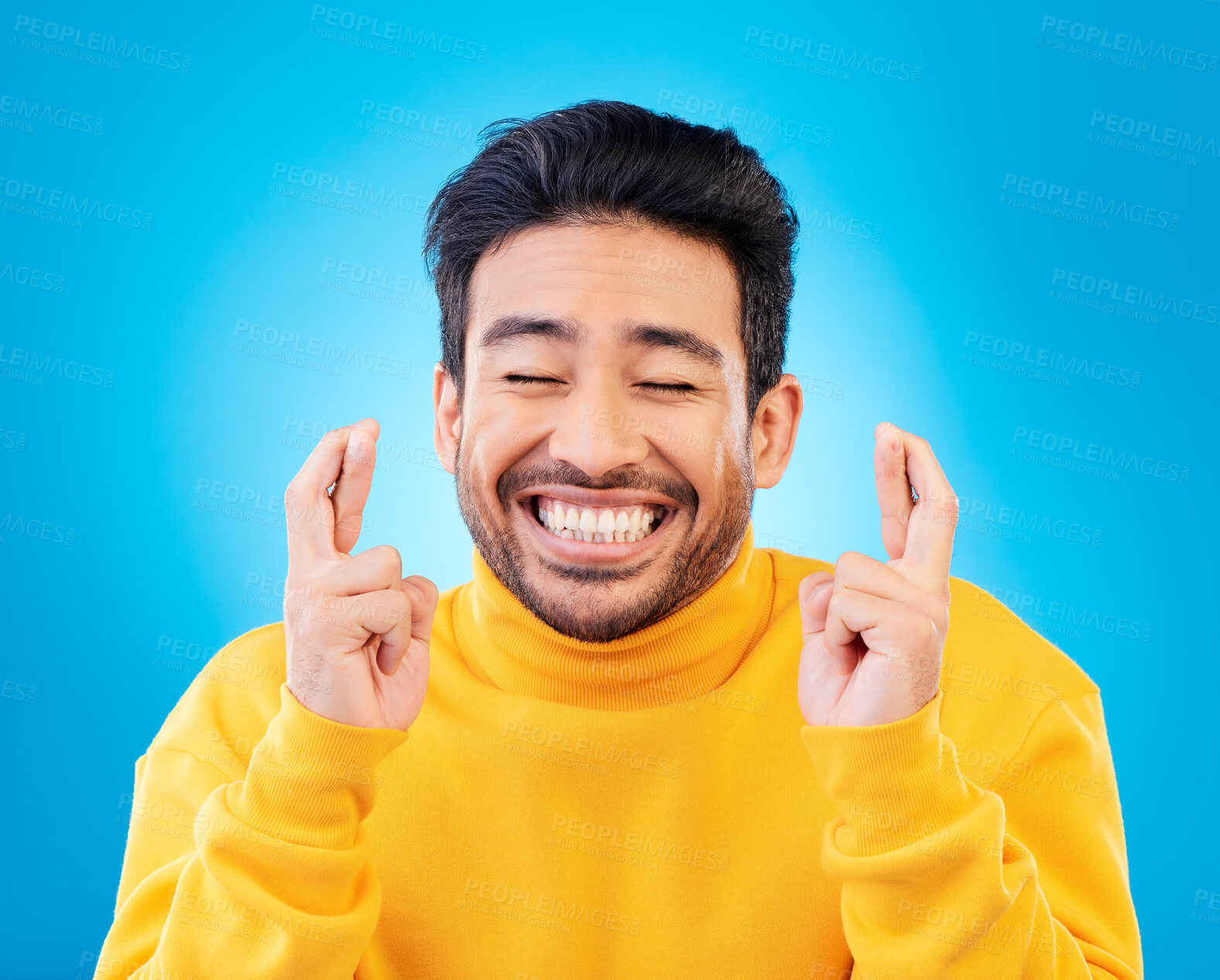 Buy stock photo Hope, man with his fingers crossed for luck and against a blue background for competition. Praying or miracle, trust and male person with hand emoji for aspiration or wish against a backdrop.
