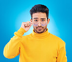 Stylish, fashion and portrait of a man with glasses, confidence and winter aesthetic. Serious style, trendy and an Asian model with fashionable eyewear isolated on a blue background in a studio