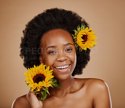 Buy stock photo Portrait, beauty and sunflower with a model black woman in studio on a brown background for cosmetics. Face, skincare or natural and a happy young female person with a flower in her afro haira
