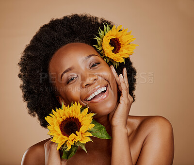 Buy stock photo Portrait, aesthetic and sunflower with a model black woman in studio on brown background for beauty. Face, skincare or natural cosmetics and a happy young female person with a flower in her afro hair