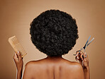 Back, comb and scissors with a black woman in studio on a brown background for a haircut. Salon, afro and haircare with a natural female model at the hairdresser for hairstyling or beauty from behind