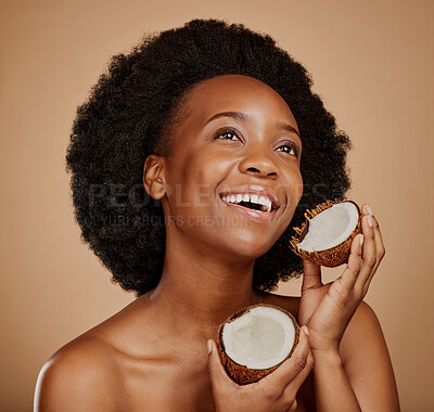 Buy stock photo Beauty, skincare and coconut with a model black woman in studio on a brown background for natural treatment. Thinking, skin and cosmetics with a happy young female person holding fruit for oil