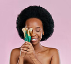 Face, makeup and black woman with brushes, eyes closed and smile in studio isolated on a pink background. Skincare, facial cosmetics and African model with tools for foundation, powder and beauty.