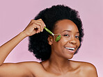 Happy, skincare and portrait of black woman with a jade roller for a facial massage or treatment. Smile, relax and African girl or model with a facial product isolated on a pink background in studio