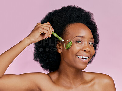 Buy stock photo Happy, skincare and portrait of black woman with a jade roller for a facial massage or treatment. Smile, relax and African girl or model with a facial product isolated on a pink background in studio