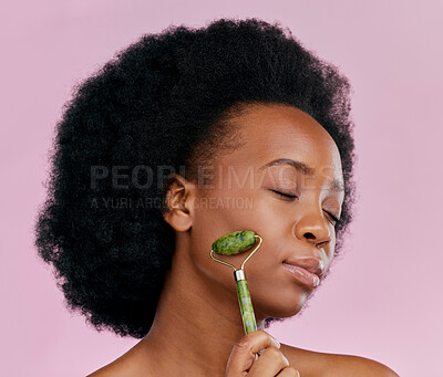 Buy stock photo Facial roller, massage and black woman with natural beauty, face care and skin glow on pink background. Female model, cosmetic tools and dermatology with jade crystal, afro hairstyle and skincare