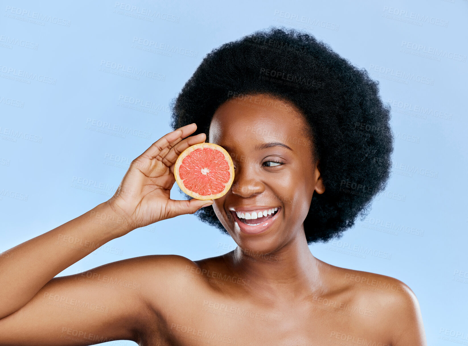 Buy stock photo Skincare, woman and grapefruit on eye for beauty, cosmetics and natural product, health or vitamin c promotion. Happy African person or model with red fruit for dermatology on studio blue background