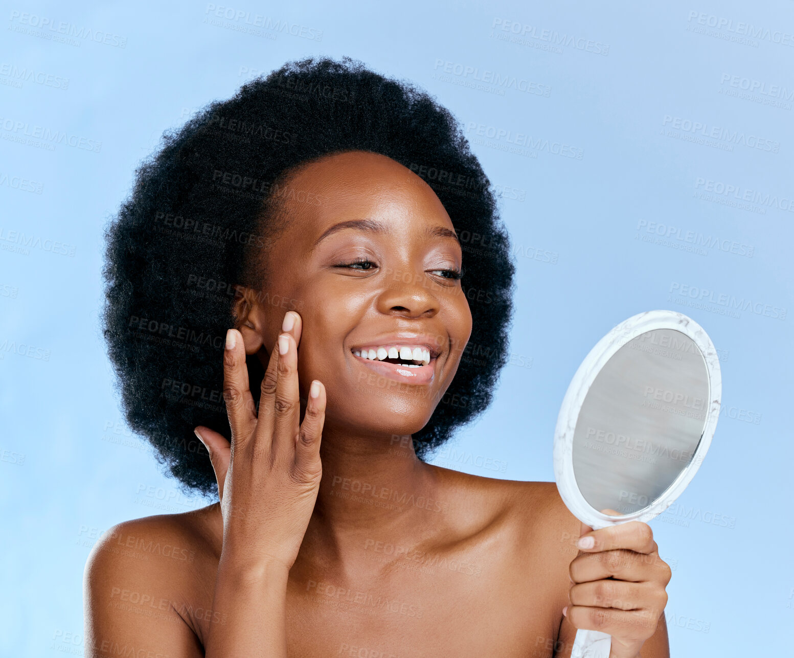 Buy stock photo Black woman, face and beauty, looking in mirror and natural cosmetics with glow isolated on blue background. Smile at reflection, facial and dermatology, African female model and afro hair in studio