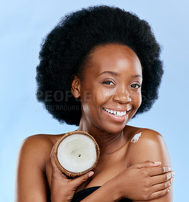 Buy stock photo Portrait, body and coconut with a model black woman in studio on a blue background for natural treatment. Beauty, skincare and smile with a happy young female person holding fruit for cosmetic oil