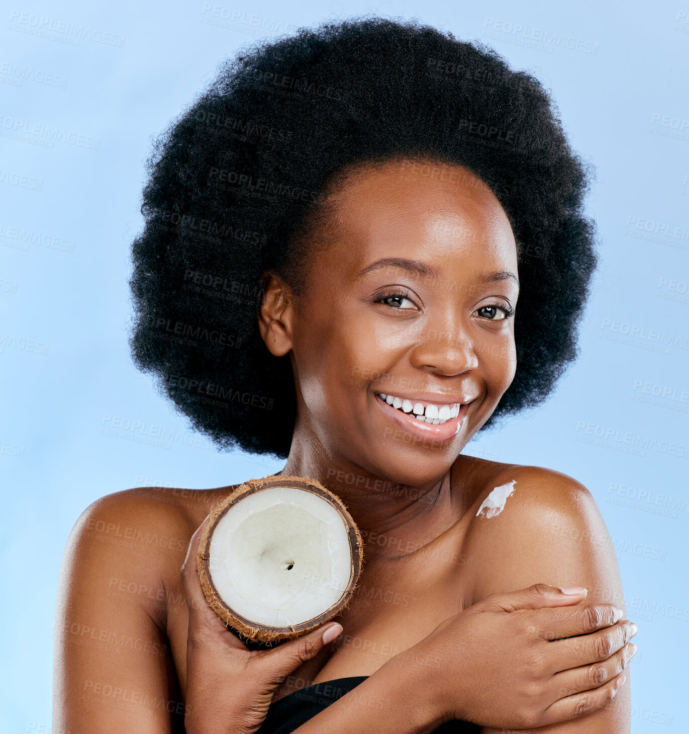 Buy stock photo Portrait, body and coconut with a model black woman in studio on a blue background for natural treatment. Beauty, skincare and smile with a happy young female person holding fruit for cosmetic oil