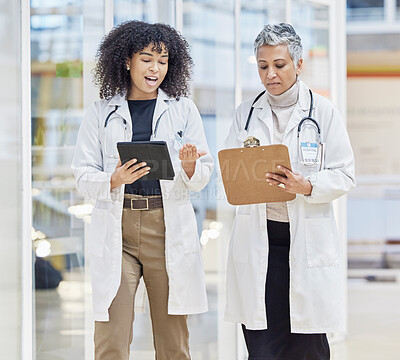 Buy stock photo Teamwork, tablet and documents with woman doctors walking in a hospital for healthcare or medical discussion. Collaboration, insurance and consulting with medicine professionals talking in a clinic