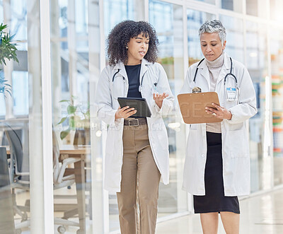 Buy stock photo Teamwork, tablet and information with woman doctors walking in a hospital for healthcare or medical discussion. Collaboration, research and consulting with medicine professionals talking in a clinic
