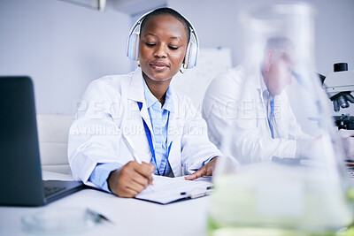 Buy stock photo Research notes, music and a black woman in a lab studying healthcare and writing a report. Innovation, education and an African scientist with headphones for a podcast while doing medical paperwork