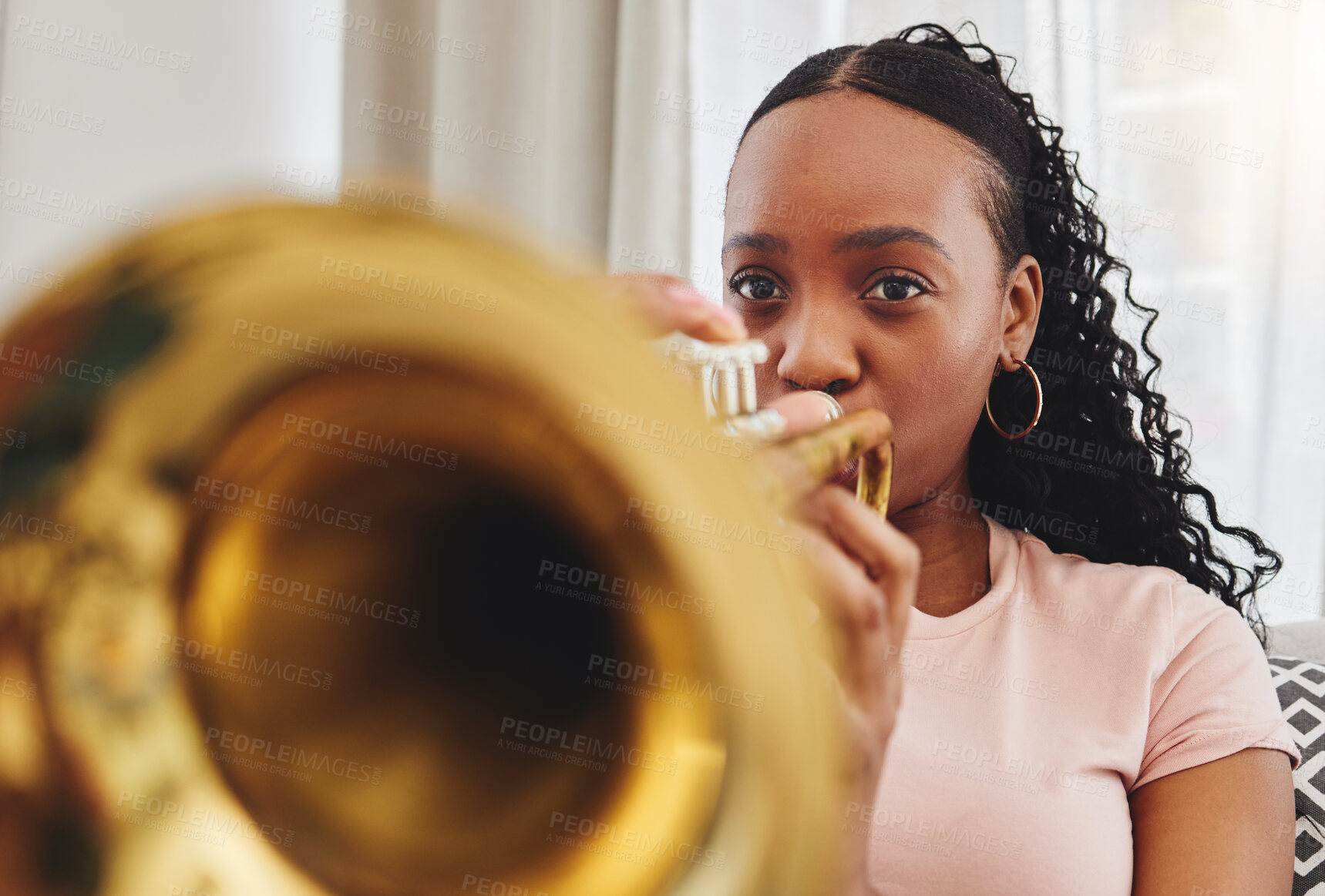 Buy stock photo Music, art and woman in home with trumpet, performance and band practice for orchestra concert in living room. Sound, creativity and jazz culture, African musician on sofa with musical instrument.