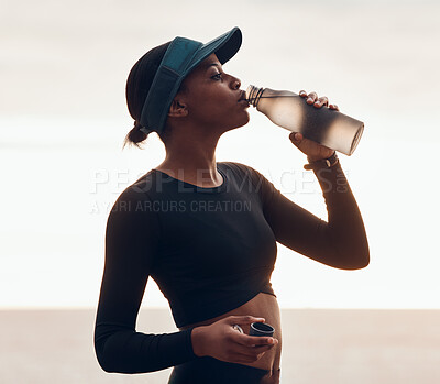 Buy stock photo Drinking water, fitness and black woman by ocean for exercise, marathon training and running. Sports, hydration and female person with liquid in bottle for thirst, cardio workout and body wellness