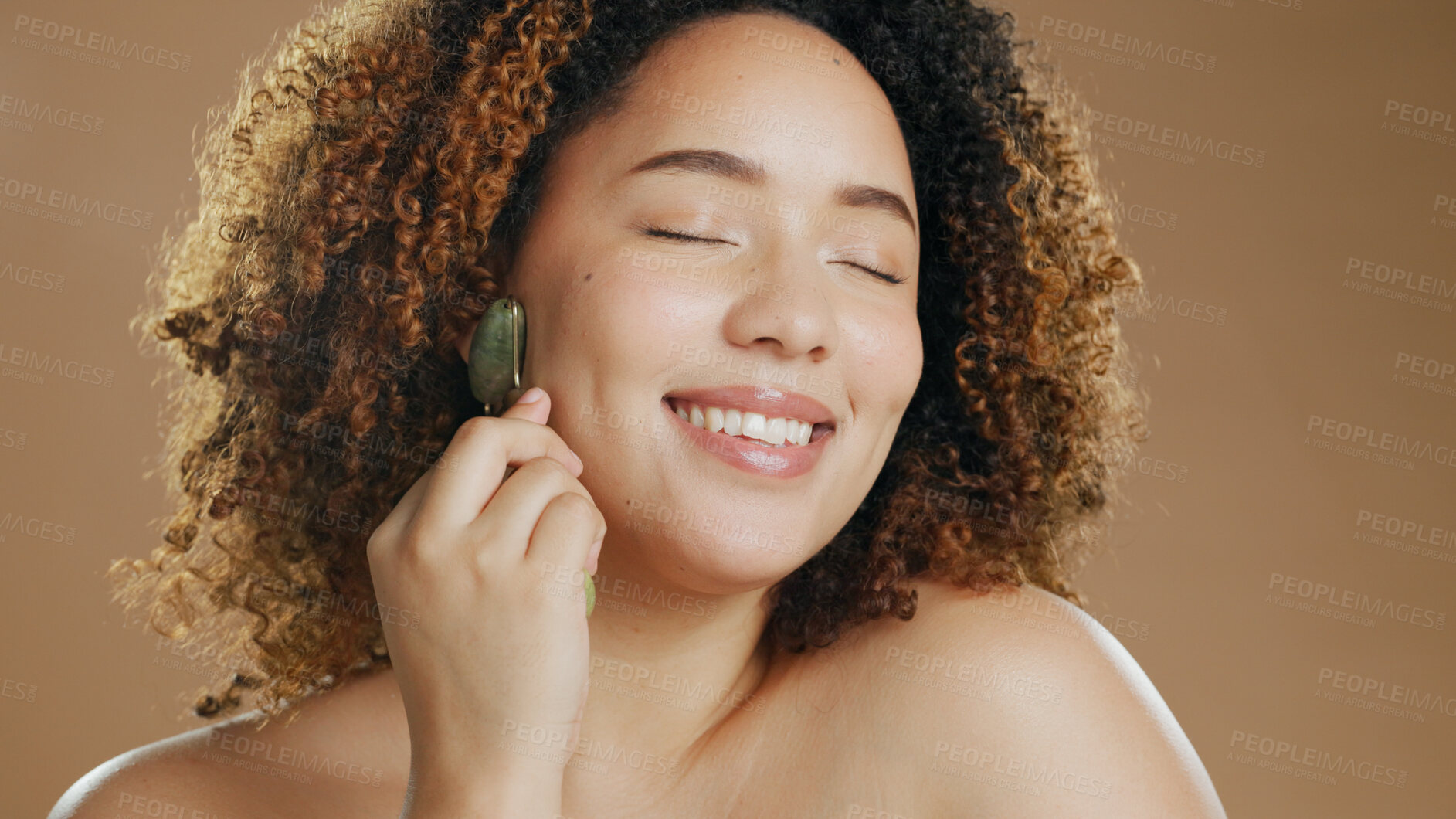 Buy stock photo Happy woman, relax or jade roller in studio for face with anti aging product or facial tool on brown background. Smile, beauty or confident girl model with cosmetics for wellness or natural skincare