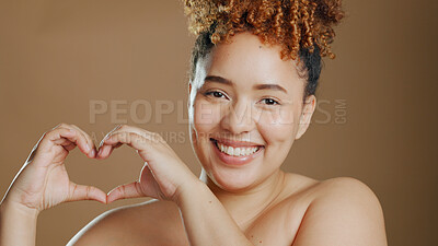 Buy stock photo Portrait, happy woman and heart sign in studio with mockup for beauty and love on brown background. African person and smile for confidence, change or results in dermatology, skincare or wellness