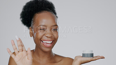 Buy stock photo Woman, model and hand with cream for face, cosmetic and beauty aesthetic with wink for happiness.  Black person, portrait and dermatology with smile for product, mockup and grey studio background